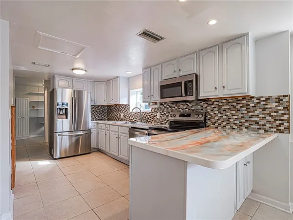 a kitchen with a stove a sink and a refrigerator with white cabinets