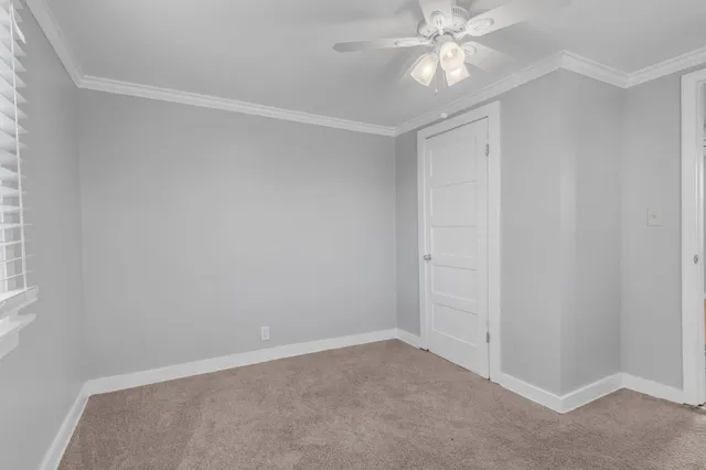 an empty room with a chandelier fan and closet area