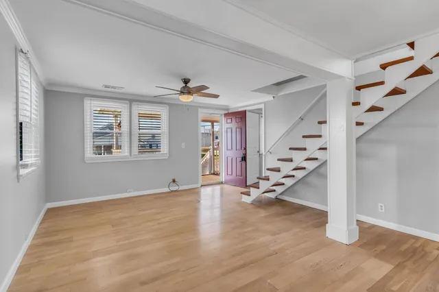 a view of an empty room with wooden floor and stairs