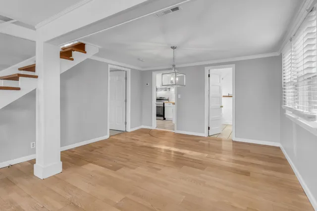 a view of an empty room with window and wooden floor
