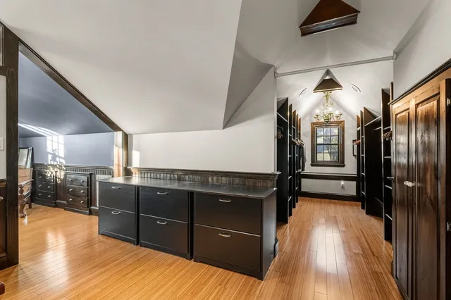 a view of a hallway to an empty room with wooden floor and windows