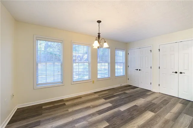 a view of an empty room with wooden floor and a ceiling fan