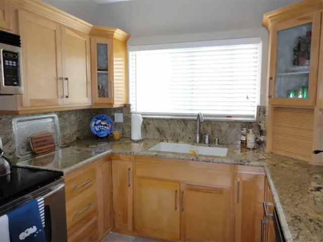 a kitchen with granite countertop a sink a stove and cabinets