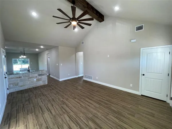 an empty room with wooden floor and a ceiling fan