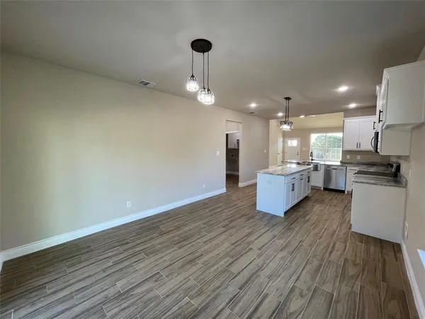 a kitchen with stainless steel appliances granite countertop a stove oven and white cabinets with wooden floor