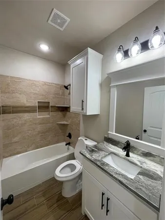 a bathroom with a granite countertop sink a toilet a mirror and bathtub
