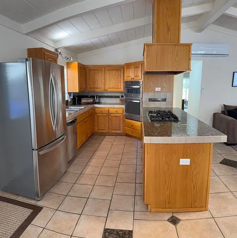 a kitchen with stainless steel appliances granite countertop a refrigerator a sink a stove top oven and cabinets