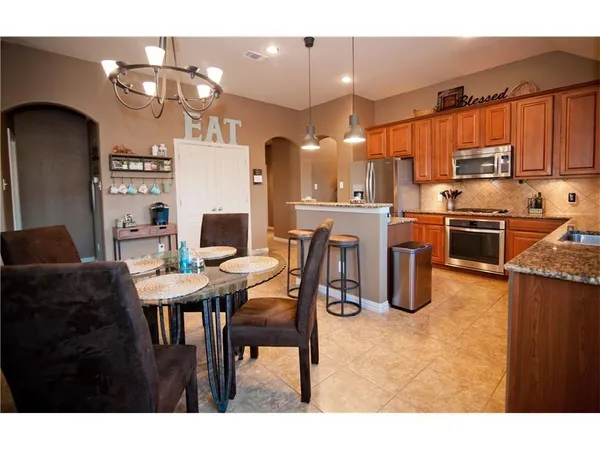 a kitchen with stainless steel appliances granite countertop a stove top oven a refrigerator and a dining table
