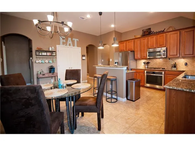 a kitchen with stainless steel appliances granite countertop a stove top oven a refrigerator and a dining table