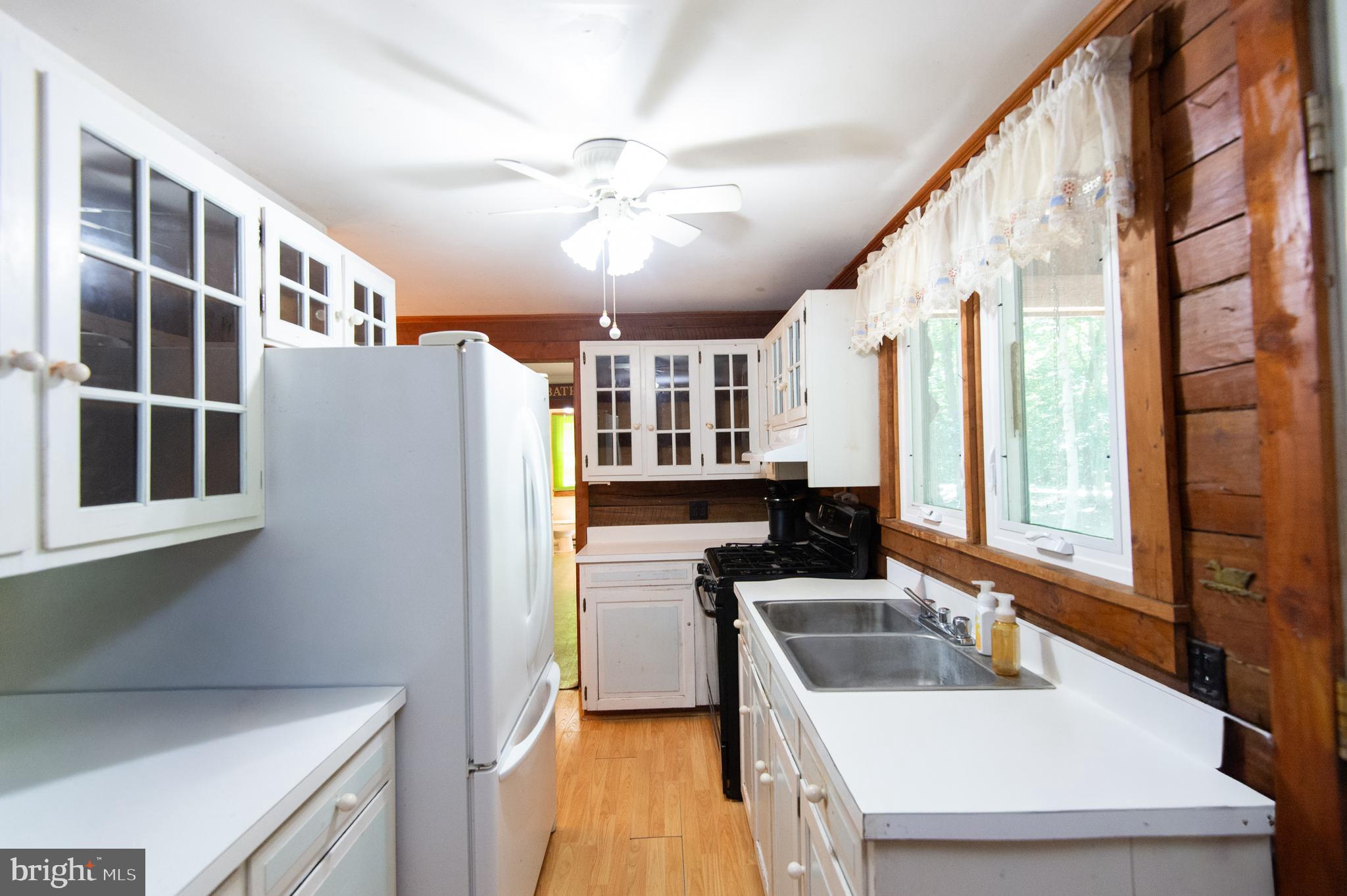 21370 Skeleton Creek Road Preston, MD 21655 - Photo 18 of 47 a kitchen with stainless steel appliances granite countertop a refrigerator a stove and a sink with wooden floor