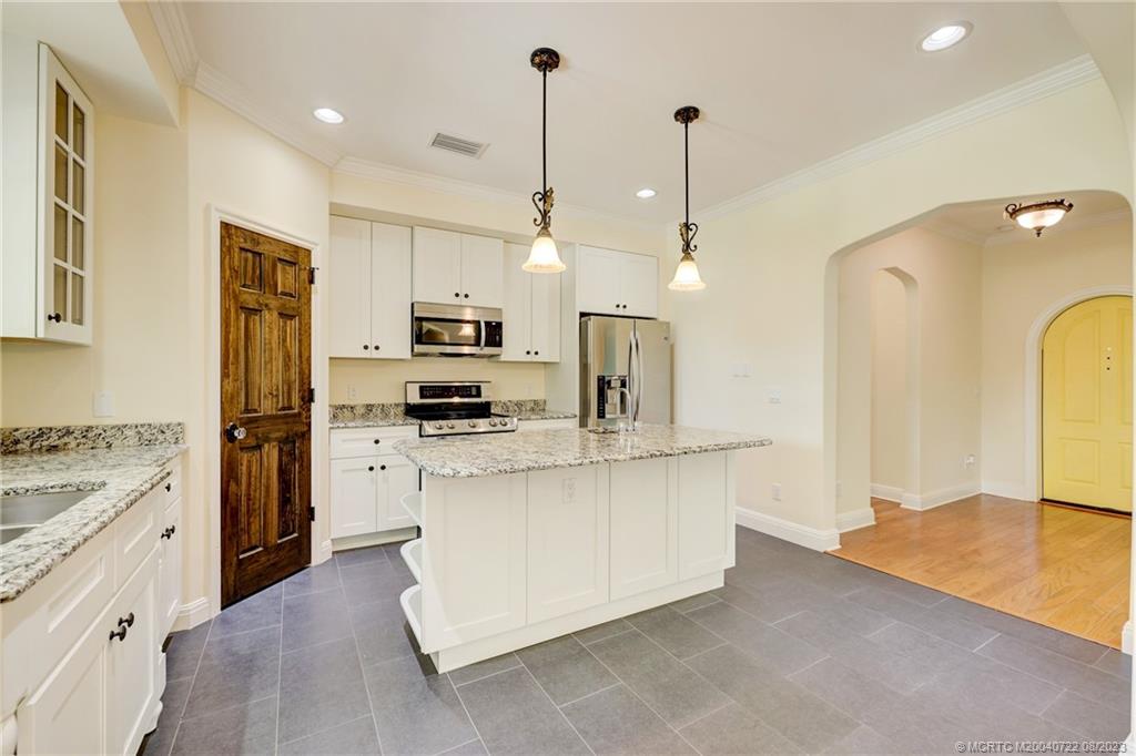 4865 Southeast Manatee Cove Road Stuart, FL 34997 - Photo 23 of 53 a kitchen with stainless steel appliances granite countertop a sink a stove a refrigerator and white cabinets with wooden floor