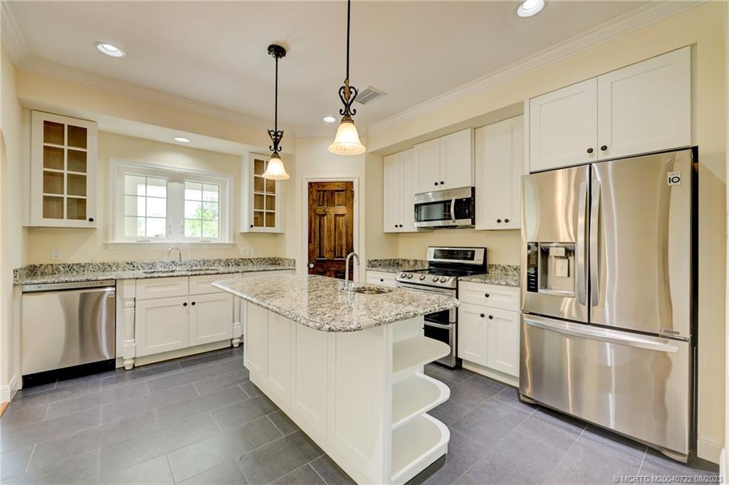 4865 Southeast Manatee Cove Road Stuart, FL 34997 - Photo 25 of 53 a kitchen with granite countertop white cabinets and white stainless steel appliances