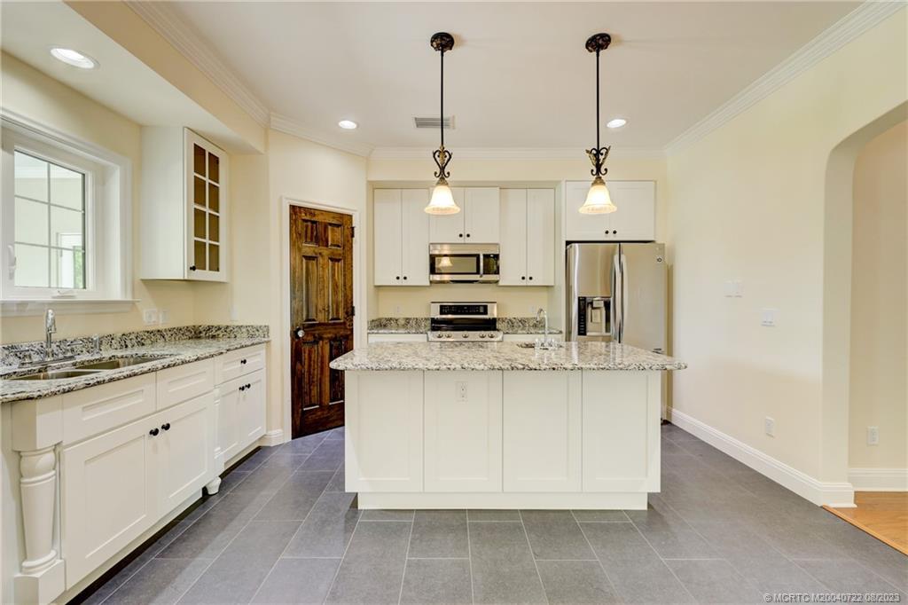 4865 Southeast Manatee Cove Road Stuart, FL 34997 - Photo 26 of 53 a kitchen with stainless steel appliances kitchen island granite countertop a stove and a refrigerator