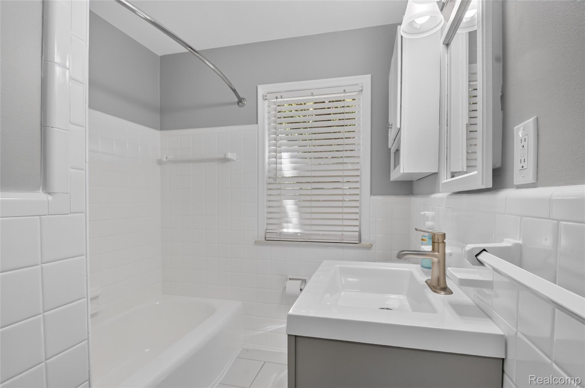12972 Callender Street Southgate, MI 48195 - Photo 19 of 40 Bathroom featuring a white bathtub, white subway tile surround, and a vanity with an integrated sink