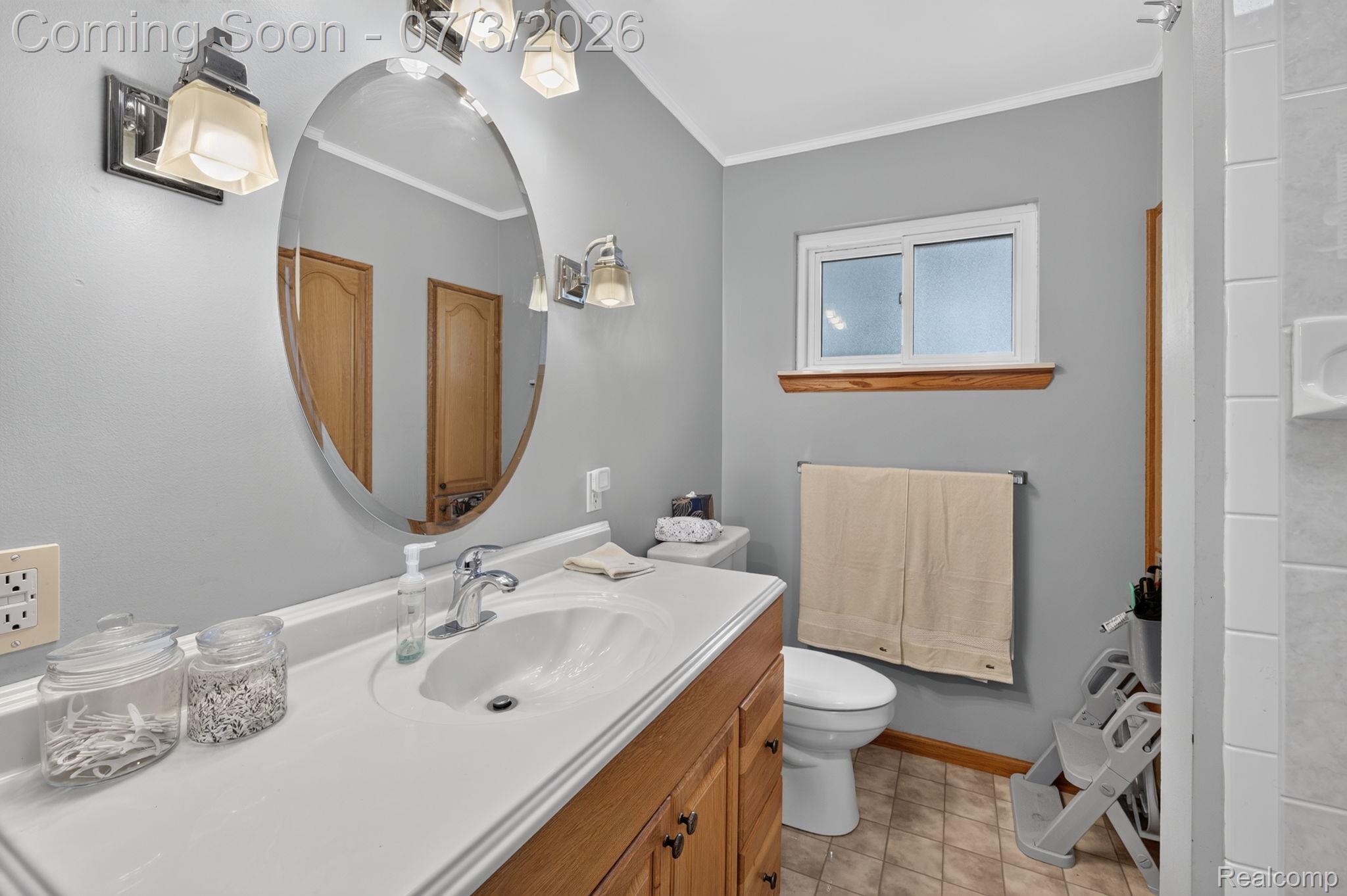 5355 North Seymour Road Flushing, MI 48433 - Photo 22 of 41 Bathroom featuring a wood-finish vanity with an integrated white sink, an oval mirror, and wall-mounted light fixtures