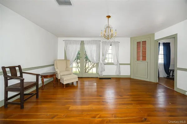 a view of a livingroom with furniture wooden floor a chandelier and windows