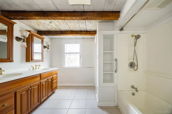 a bathroom with a double vanity sink a large mirror and a bathtub