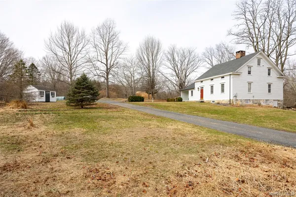 a view of a white house with a yard covered with snow
