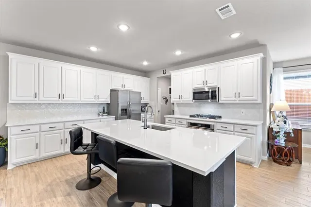 a kitchen with a sink a stove a refrigerator cabinets and dining table