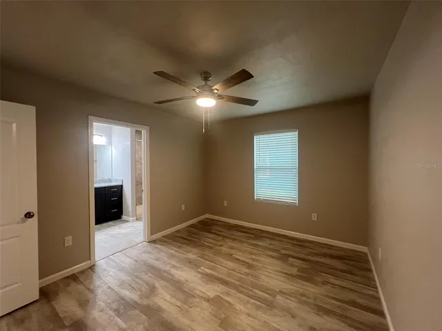 a view of an empty room with window and chandelier fan