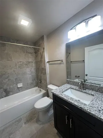 a bathroom with a granite countertop sink a toilet and shower