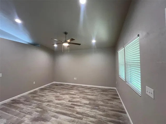en empty room with windows and ceiling fan