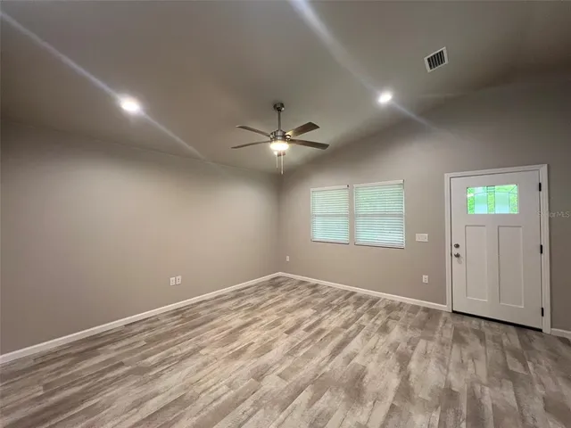 an empty room with windows and ceiling fan