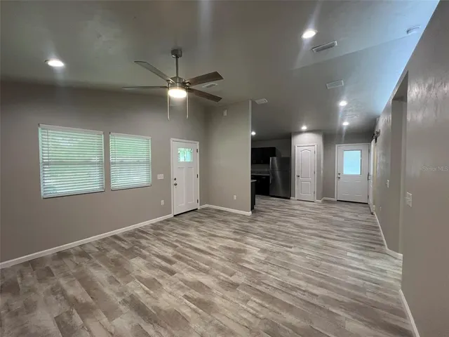 an empty room with kitchen and windows