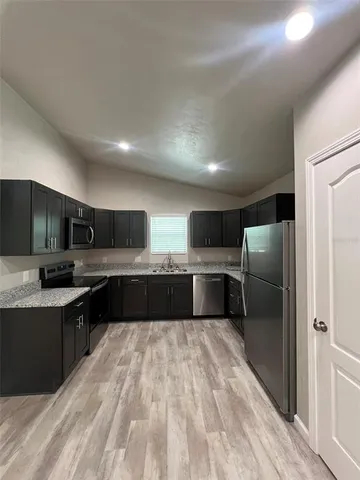 a large kitchen with stainless steel appliances double vanity and a refrigerator