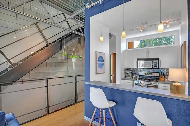 a kitchen with stainless steel appliances kitchen island granite countertop a stove a refrigerator and a dining table with wooden floor