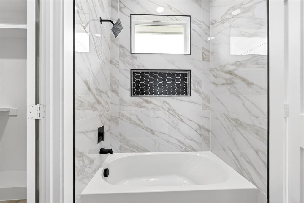 120 Springwood Road Enchanted Oaks, TX 75156 - Photo 26 of 37 Bathtub and shower combination featuring white marble-look wall tiling, a black hexagonal tile niche, and matte black fixtures
