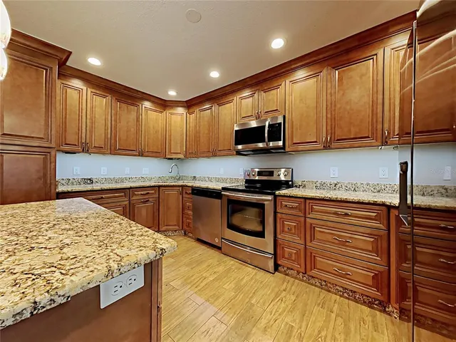 a kitchen with kitchen island granite countertop a sink stove and refrigerator