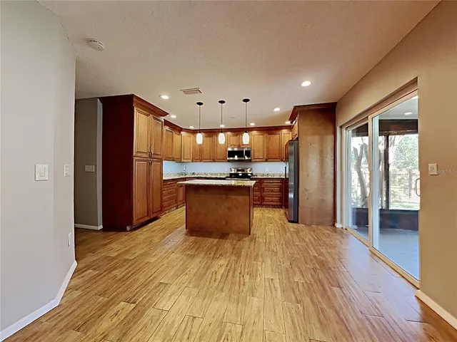 a large kitchen with stainless steel appliances granite countertop a refrigerator and a sink