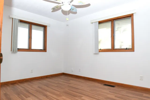 a view of an empty room with wooden floor and closet
