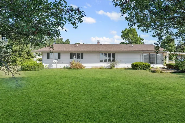 a front view of a house with garden and trees