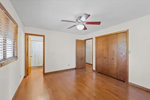 a view of empty room with wooden floor and fan
