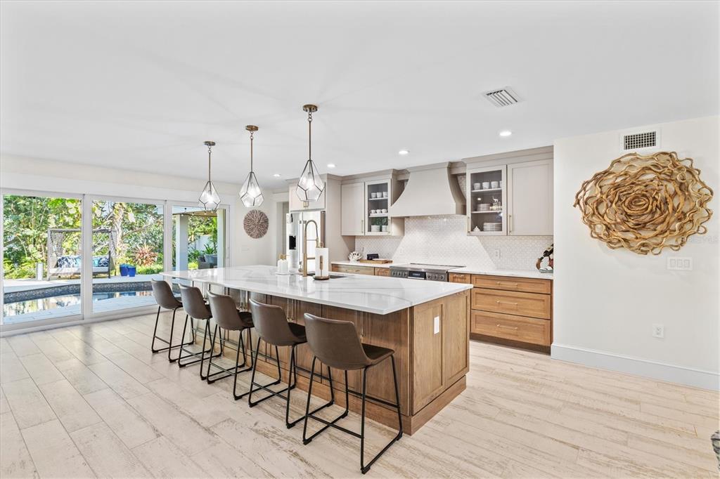 506 58th Street Holmes Beach, FL 34217 - Photo 20 of 95 a view of a kitchen with kitchen island granite countertop wooden floor stainless steel appliances and dining table