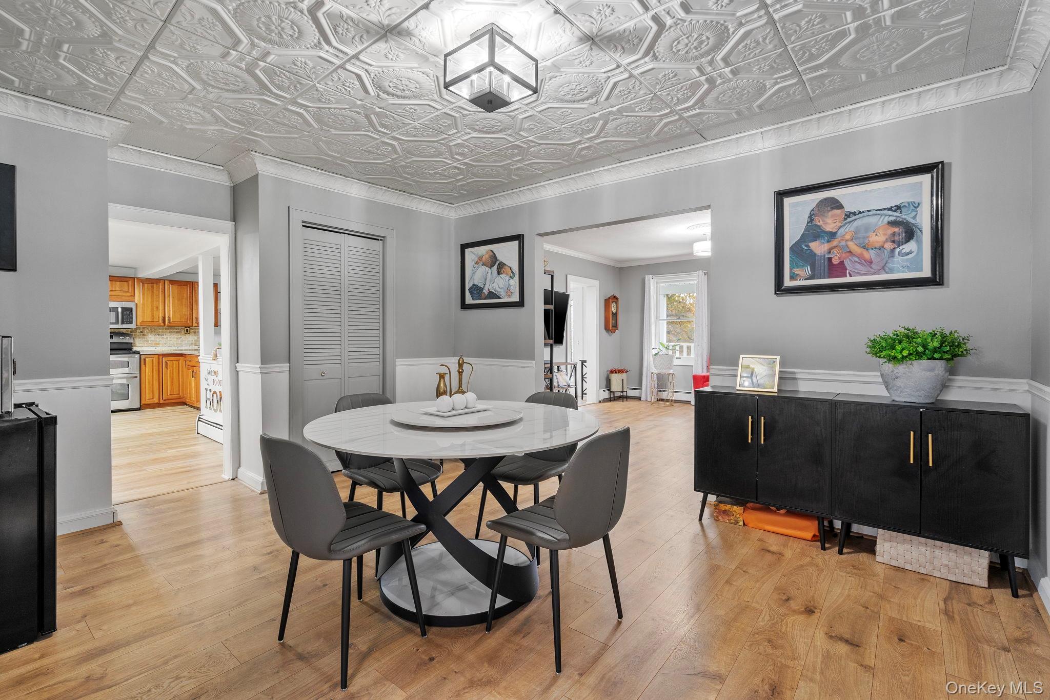 168 Fostertown Road Newburgh, NY 12550 - Photo 19 of 38 Dining space featuring light wood-style floors, ornamental molding, an ornate ceiling, and a wainscoted wall
