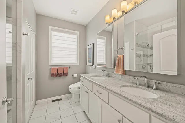 a bathroom with a granite countertop sink mirror and a toilet