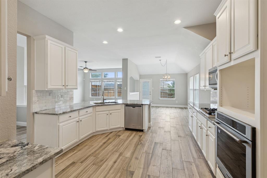 a large kitchen with a lot of counter space and wooden floor