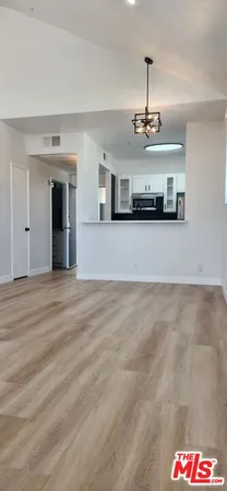 a view of an empty room with wooden floor and a fireplace