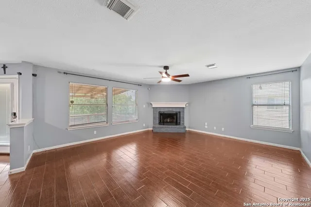 an empty room with windows and fireplace