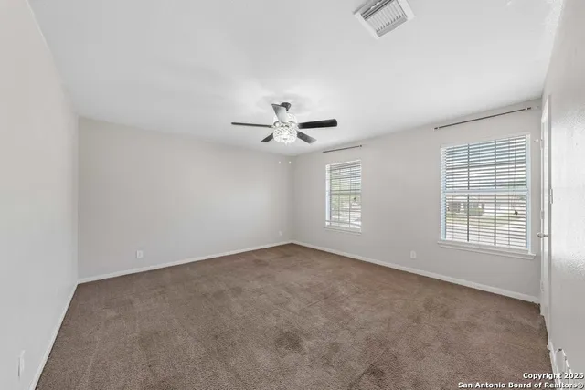 an empty room with windows and ceiling fan