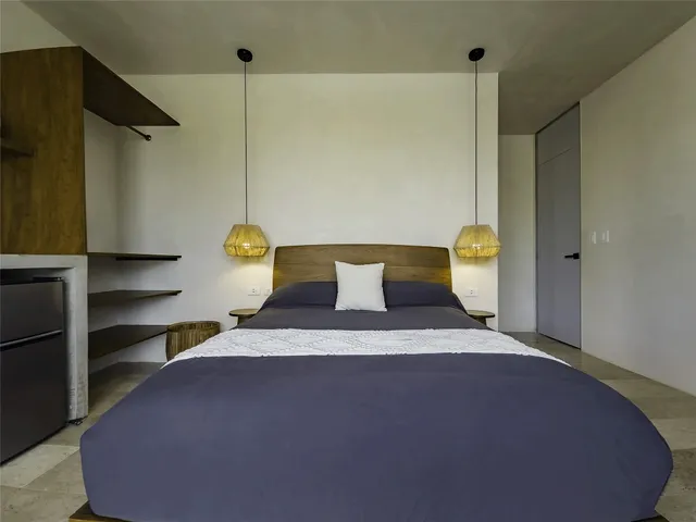 a bedroom with a bed and a potted plant on the dresser