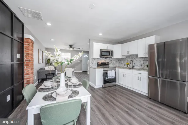 a kitchen with a refrigerator a stove top oven a sink dishwasher and white cabinets with wooden floor