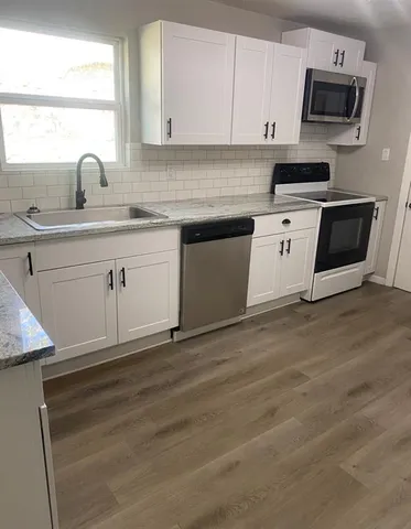 a kitchen with granite countertop white cabinets and white appliances