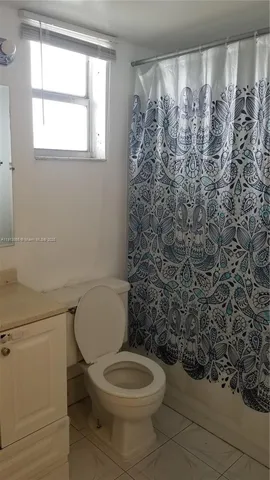 a white toilet sitting next to a shower curtain