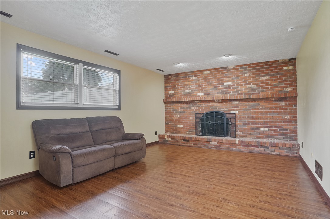 3262 Wright Road Northwest Uniontown, OH 44685 - Photo 28 of 37 Living area with wood finished floors, a textured ceiling, and a brick fireplace