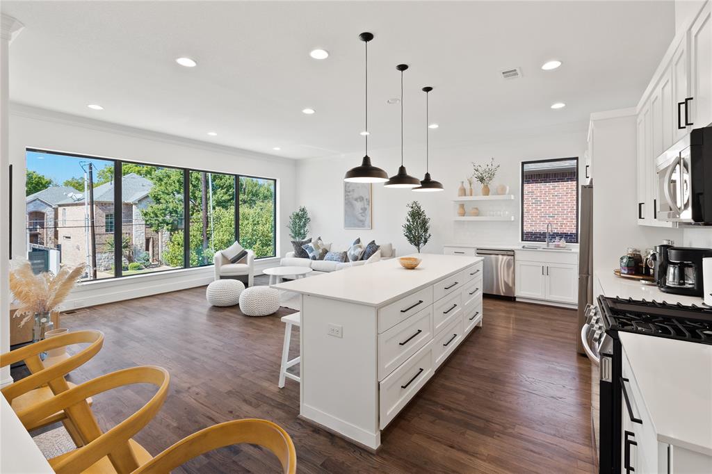 5014 Mission Avenue, Unit A Dallas, TX 75206 - Photo 2 of 26 a large white kitchen with a large window a island a stove a wooden floor and a couch