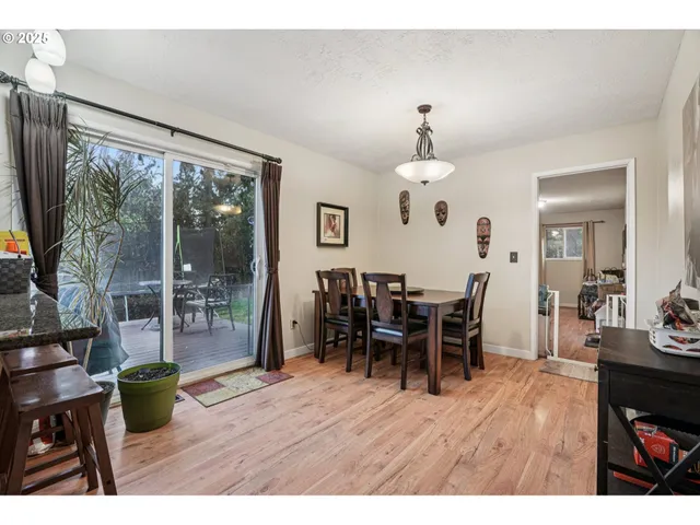 a dining room with wooden floor a chandelier a wooden table and chairs